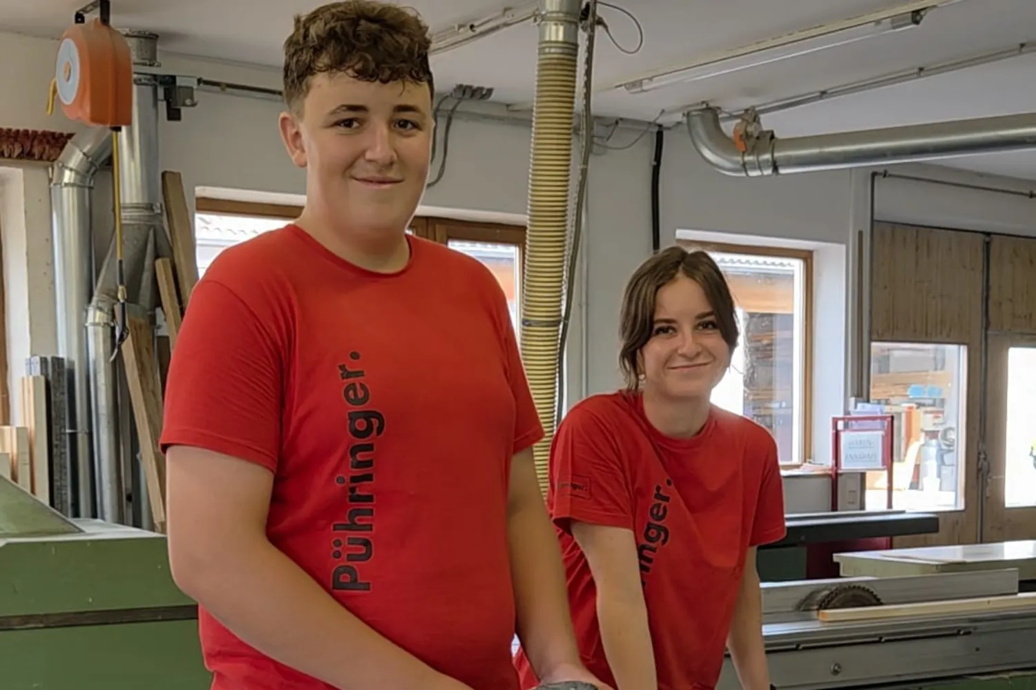 Zwei junge Menschen. Links der neue Lehrling mit einem roten, kurzärmeligen Pühringer T-Shirt. Rechts Ferialpraktikantin mit einem roten, kurzärmeligen Pühringer T-Shirt.